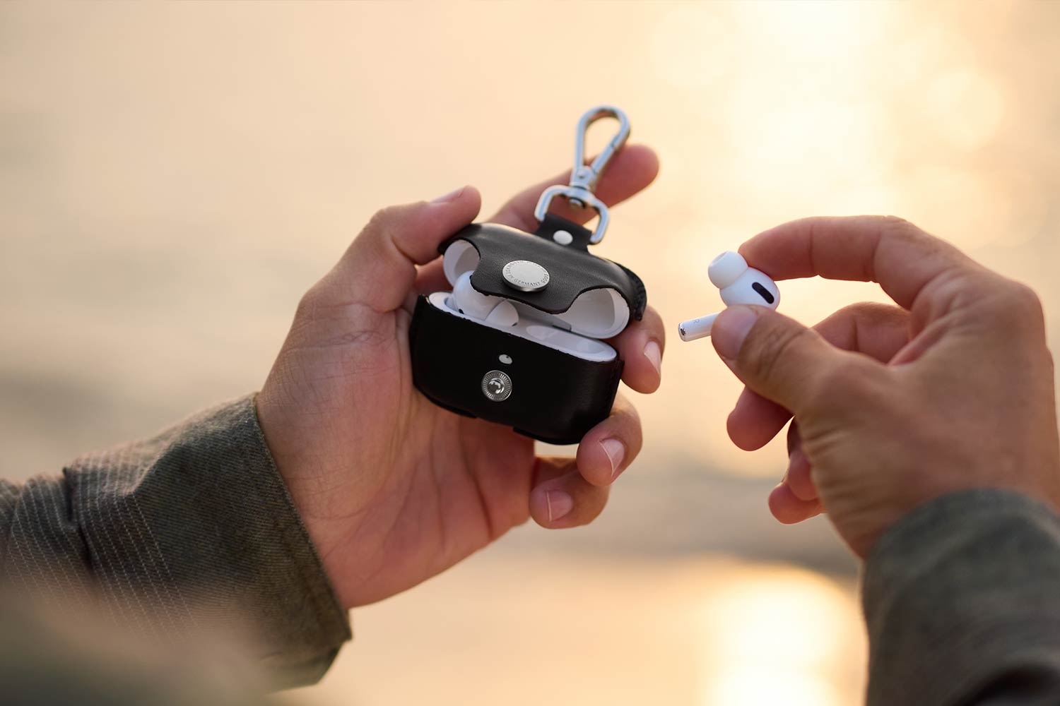 Zwei Hände halten eine Airpods Hülle aus Leder in den Händen