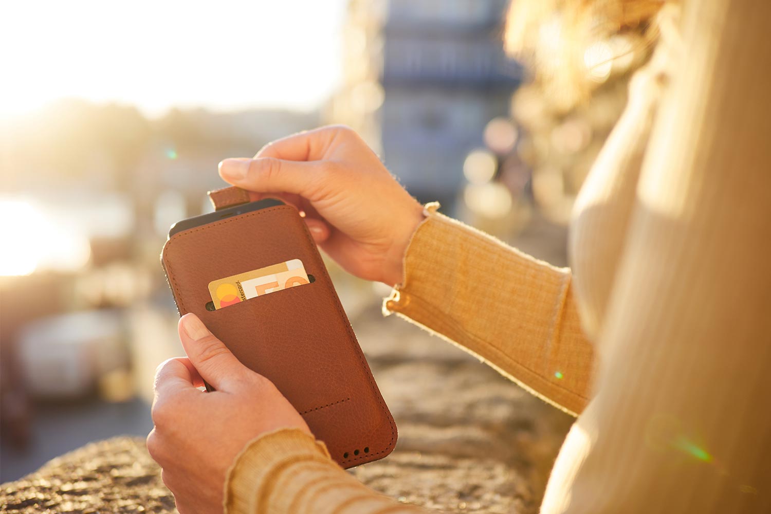 A woman holds an iPhone leather case in her hand and pulls out the device