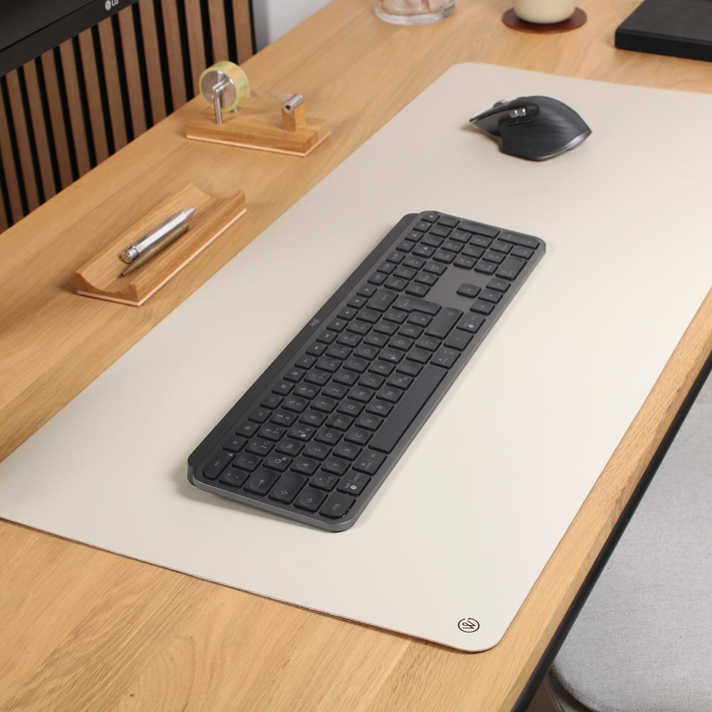 A desk mat made of white linoleum from Good WIlhelm lies on a wooden table