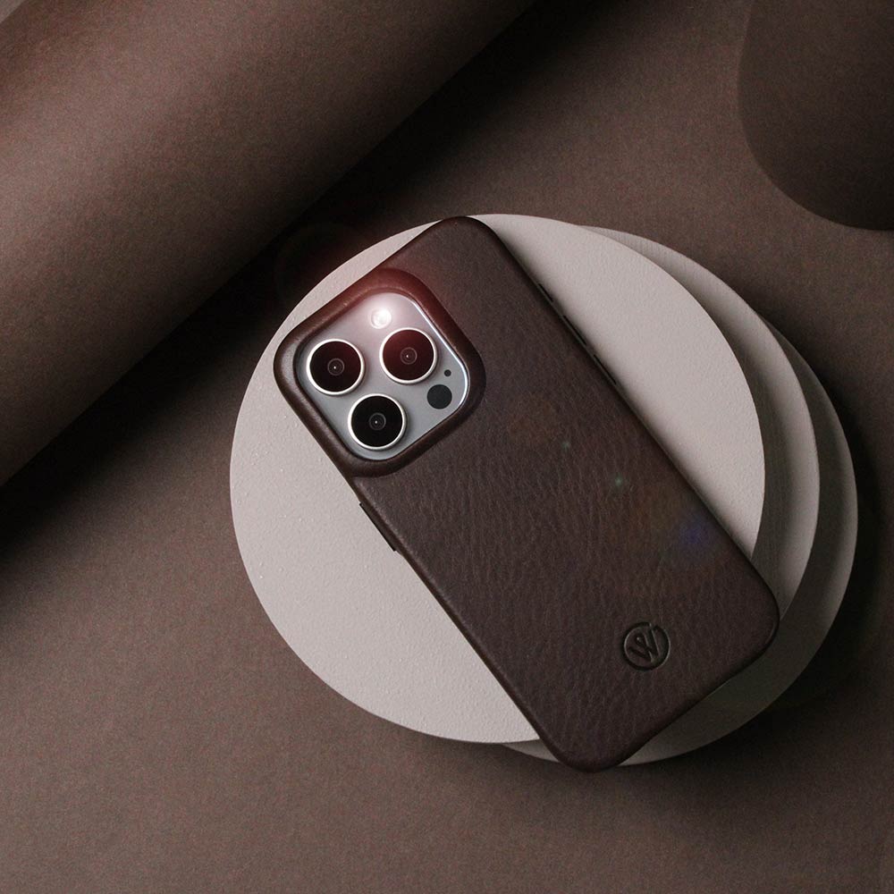 Dark brown iPhone case made of high-quality leather, lying on a table with decorative wooden slices