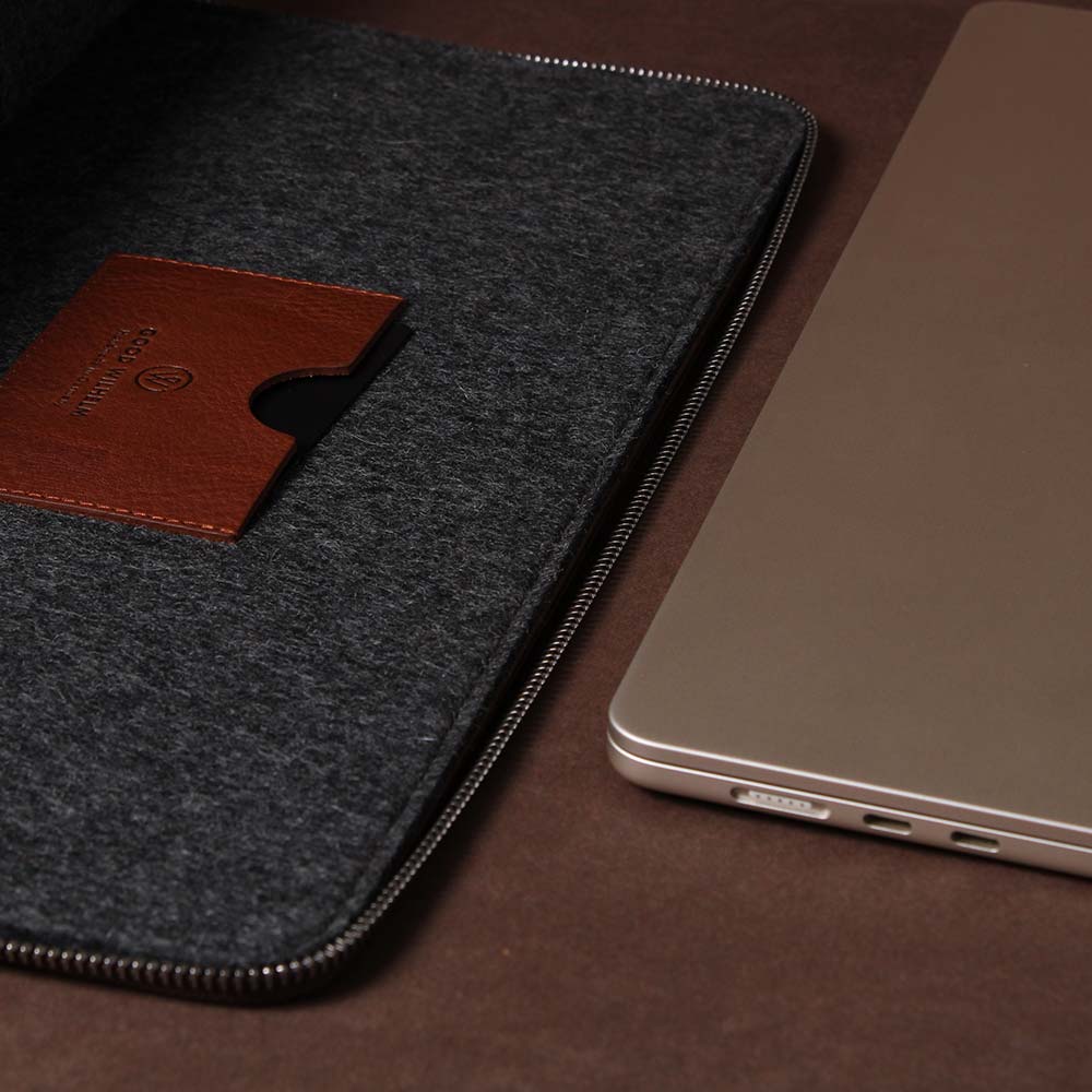 Eine Macbook Hülle aus Filz und Leder liegt neben einem Macbook
