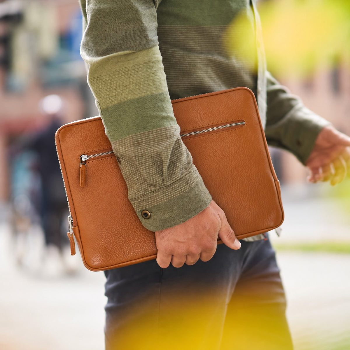Mann trägt MacBook Pro Hülle FRIEDRICH in cognac braunem Leder von Goodwilhelm unter dem Arm