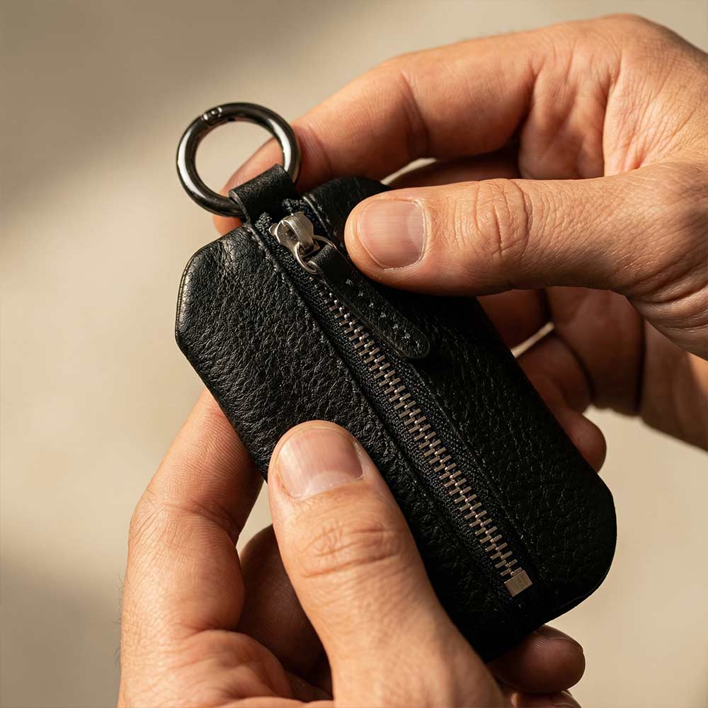 Schlüsseltasche aus Leder in Schwarz von Good Wilhelm in der Hand mit Reißverschluss