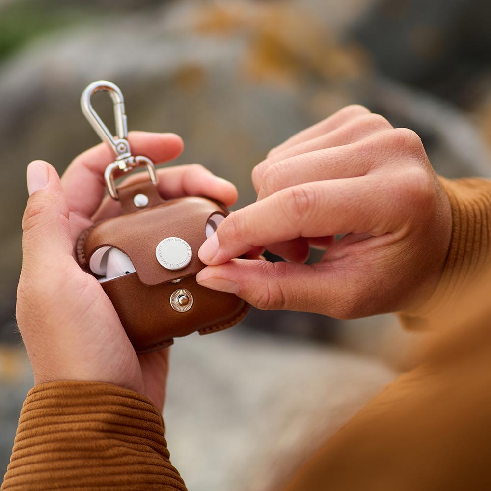 Zwei Hände halten eine Airpods Pro Hülle aus Leder in den Händen