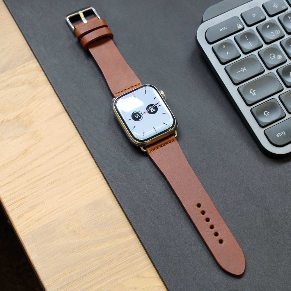 Auf einem Tisch liegt eine Apple Watch mit Lederarmband in der Farbe Cognac von Goodwilhelm