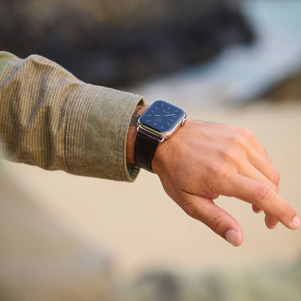 A man wears an Apple Watch with a black leather strap from Goodwilhelm on his wrist