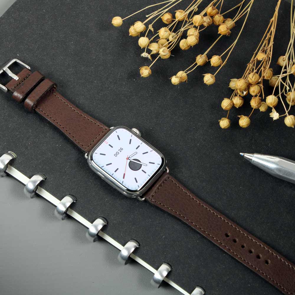 On a table lies a watch with a dark brown leather strap from Goodwilhelm