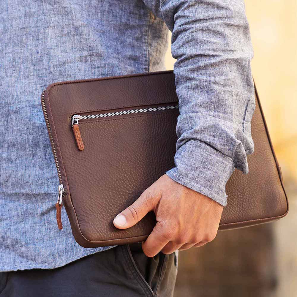 Macbook bag in dark brown leather is worn under the arm
