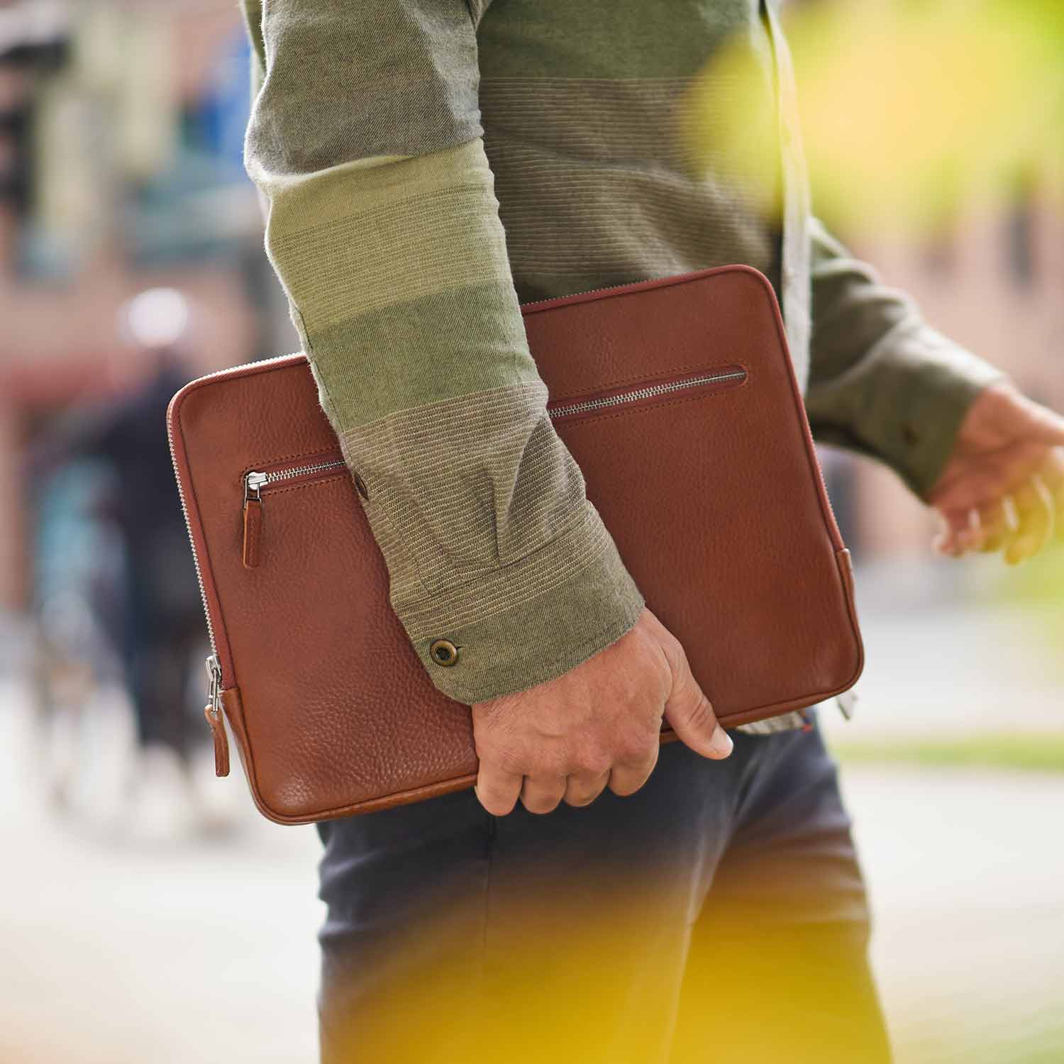 A man carries a leather Surface Laptop sleeve under his arm