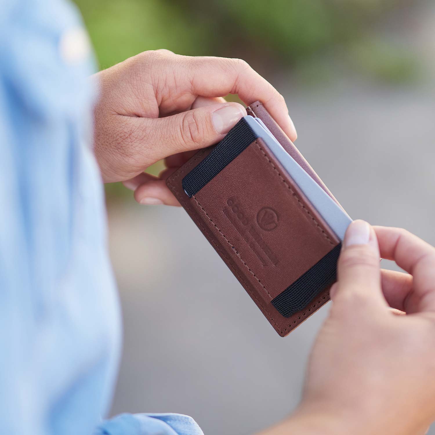 Two hands hold mini wallet OTTO from Goodwilhelm in the color cognac
