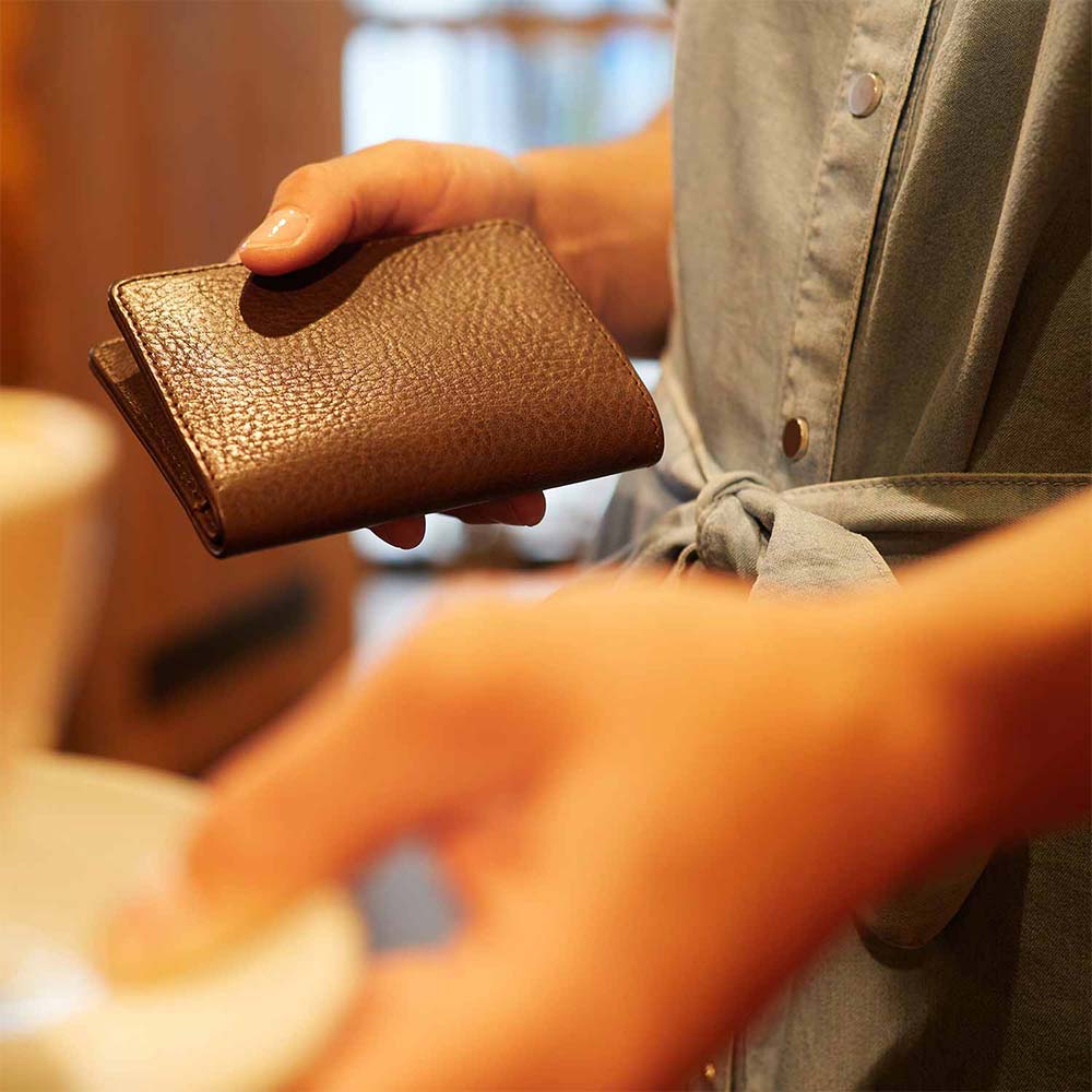 A woman holds a leather wallet in her hands