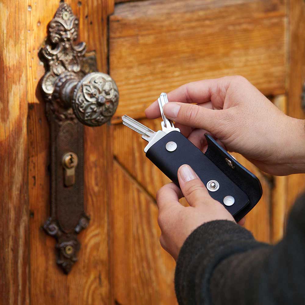 Two hands hold a leather key case in black from Goodwilhelm