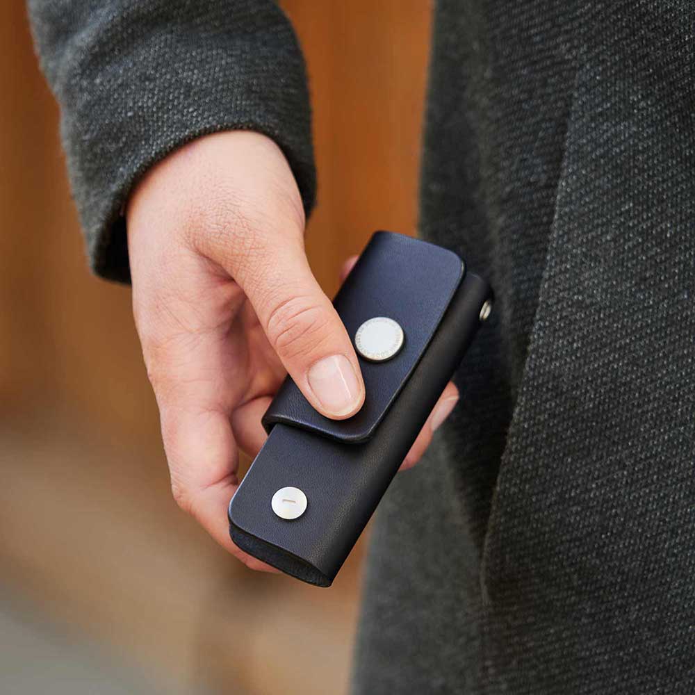 One hand holds a key bag in the color black from Goodwilhelm