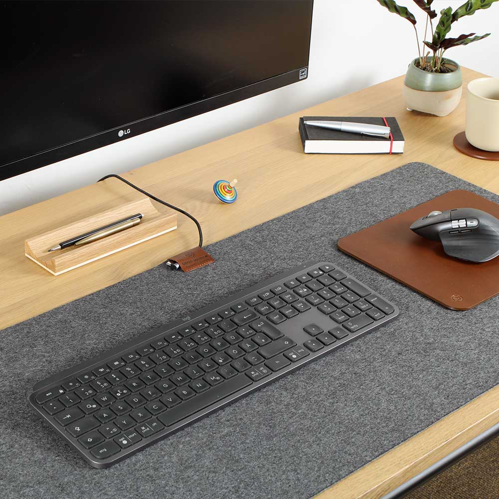 A felt desk pad with a leather mouse pad lies on a table