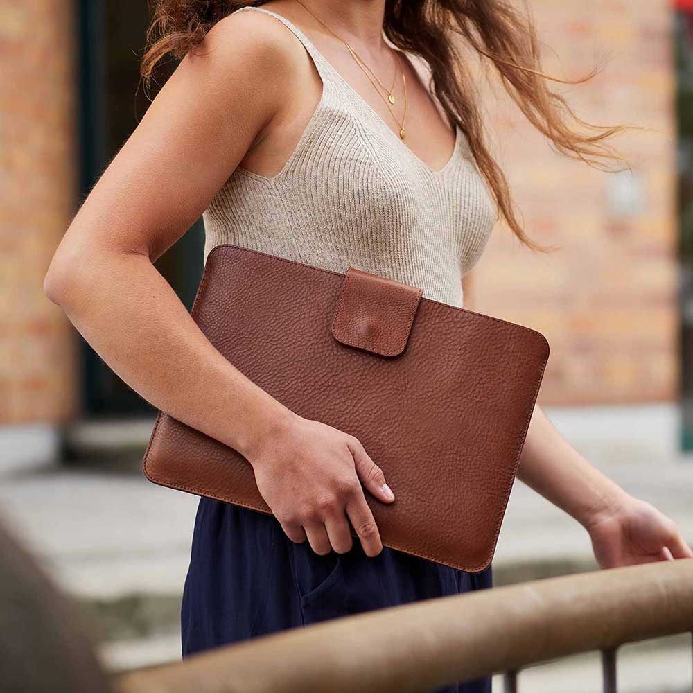 A woman carries a light brown laptop case under her arm
