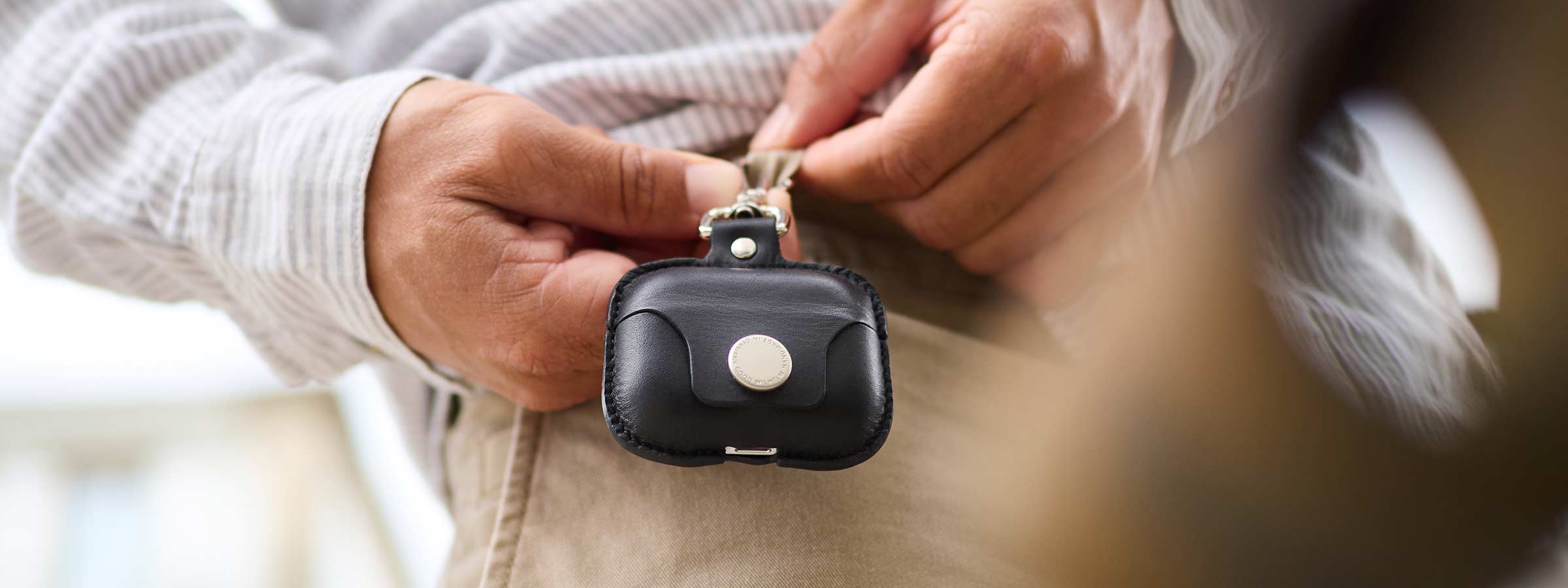 A man attaches his Good Wilhelm leather Airpods Pro case to his belt pouch