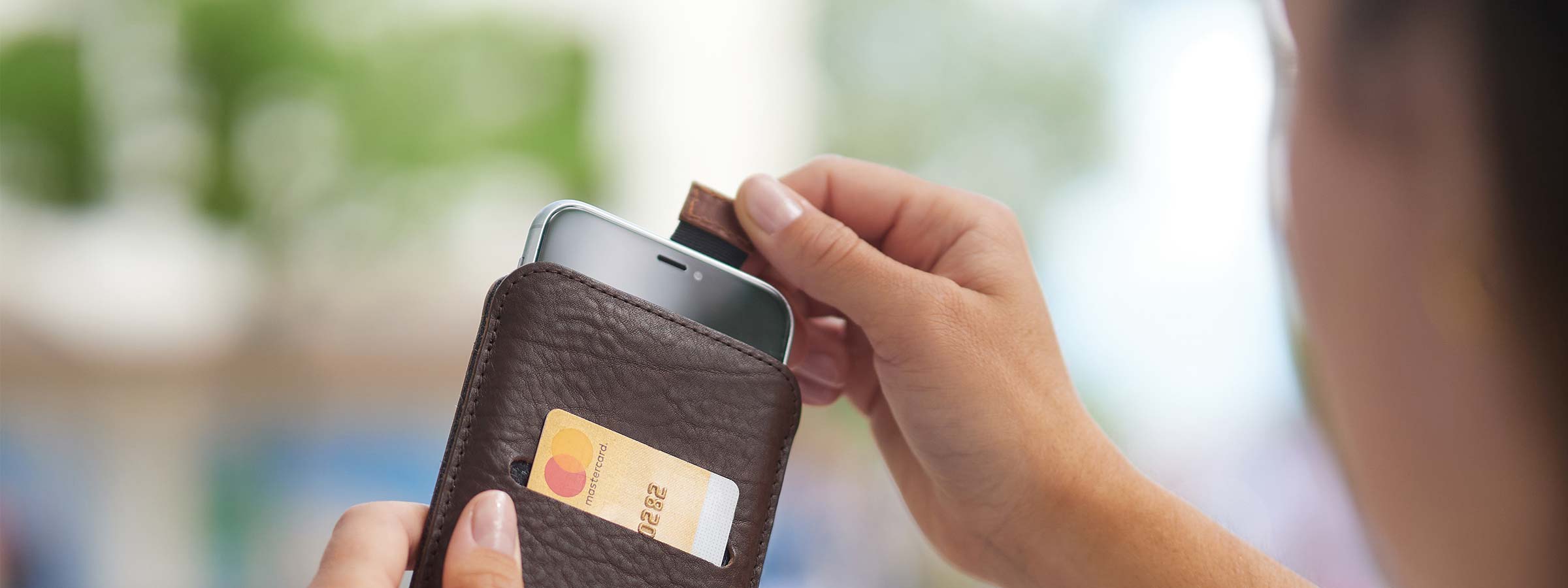 A woman pulls her iPhone 16 Pro out of a leather case