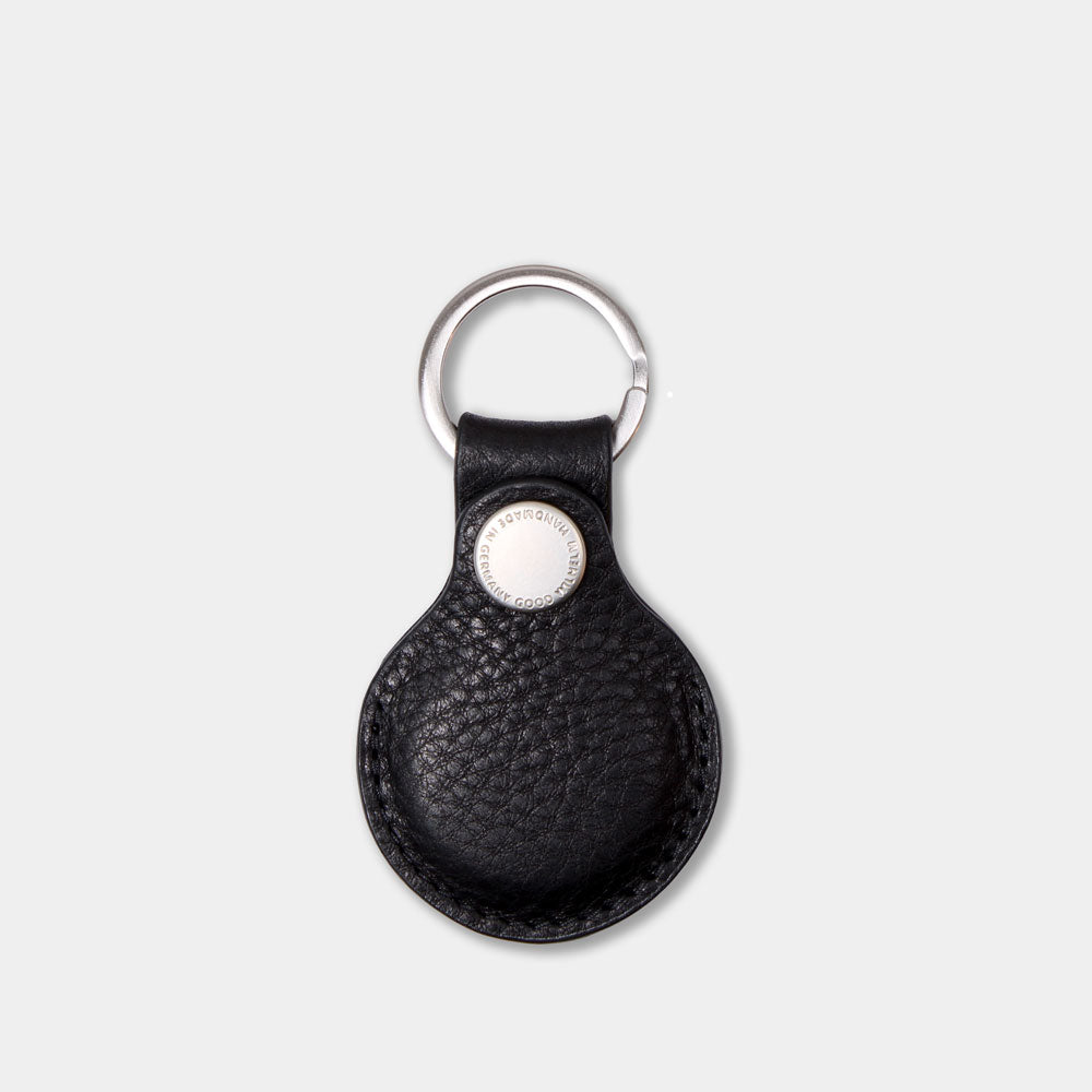 AirTag Anhänger aus pflanzlich gegerbtem Leder in Schwarz – Vorderansicht mit geschlossenem Prym-Druckknopf und Good Wilhelm Monogramm