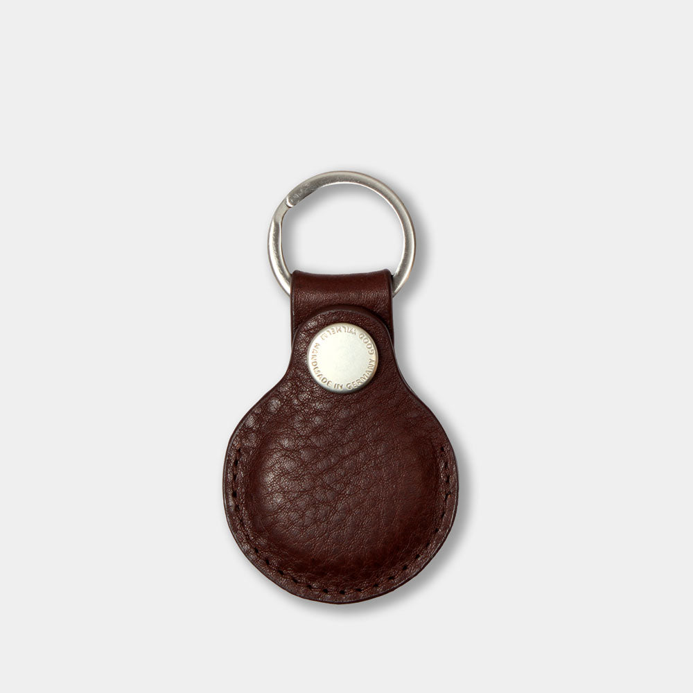 AirTag Anhänger aus pflanzlich gegerbtem Leder in Chocolate Braun – Vorderansicht mit geschlossenem Prym-Druckknopf und Good Wilhelm Monogramm