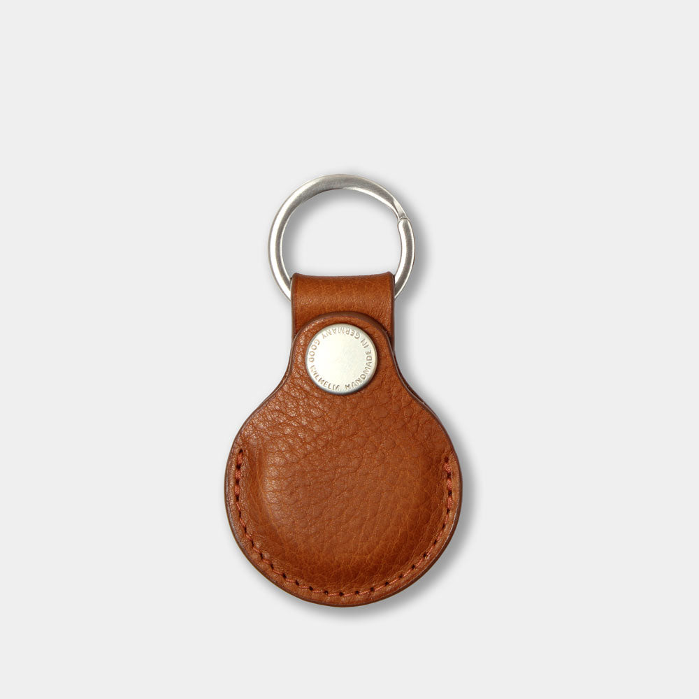 AirTag Anhänger aus pflanzlich gegerbtem Leder in Cognac – Vorderansicht mit geschlossenem Prym-Druckknopf und Good Wilhelm Monogramm