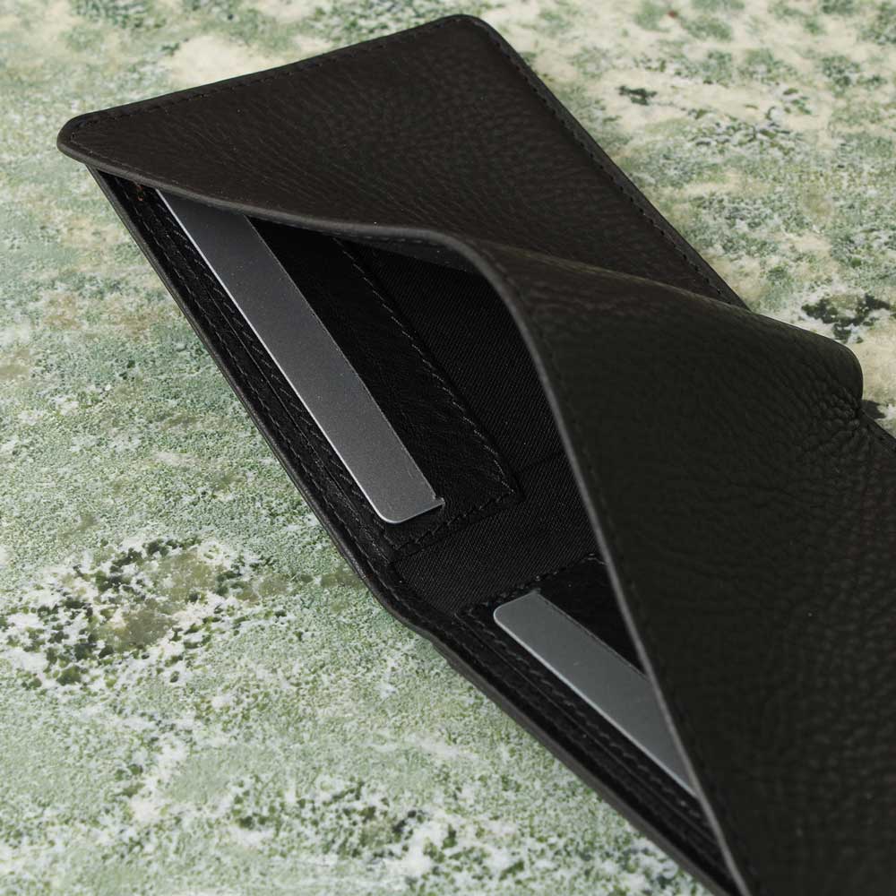 Men's wallet made of leather in black with coin pocket and card pocket in the bill compartment, side view, presented on green marble - Good Wilhelm