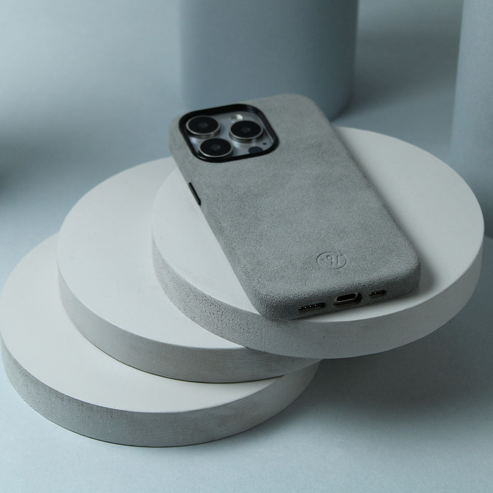 Auf einem Tisch liegt eine iPhone Pro 15 Hülle aus Alcantara in Grau