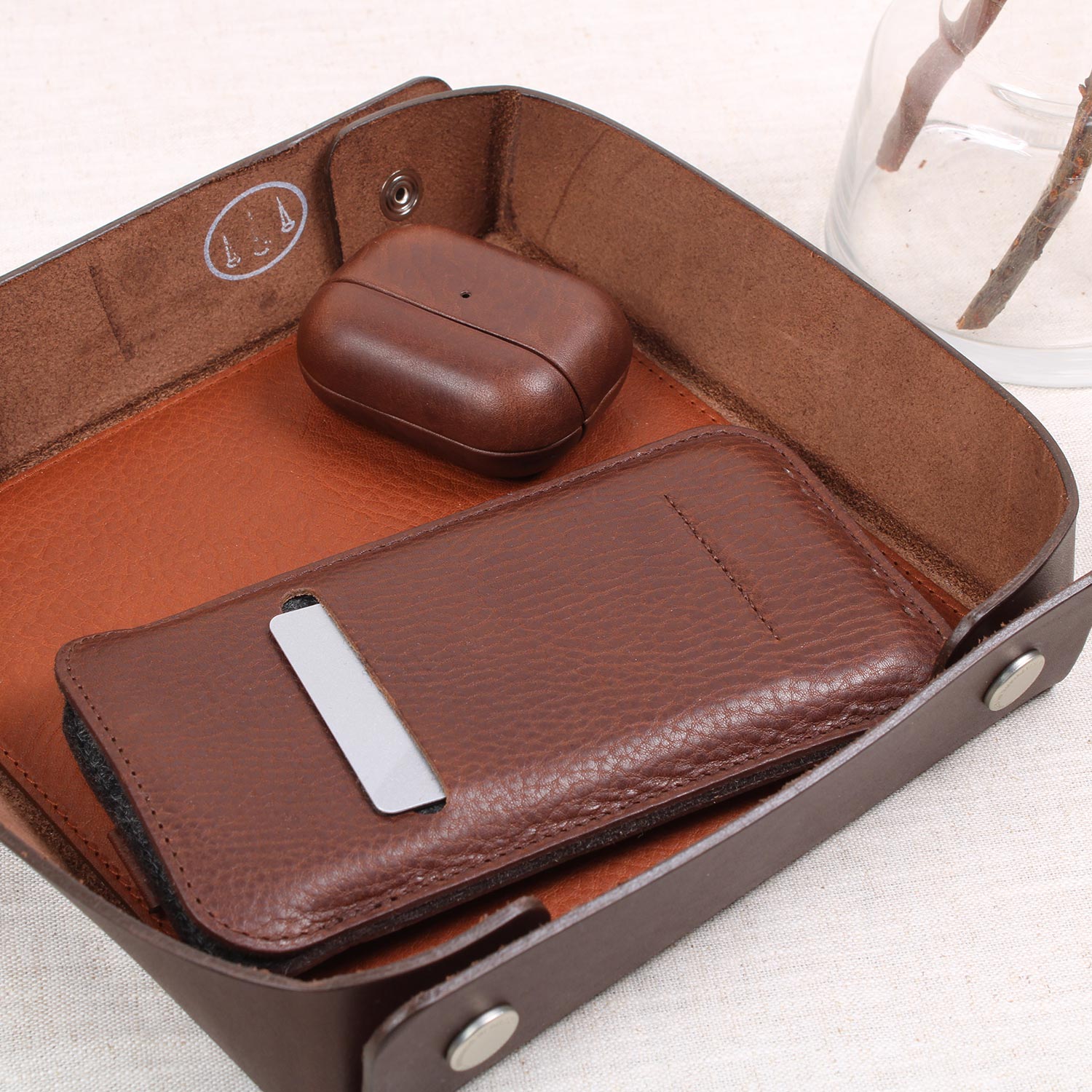 Exklusives iPhone Leder Sleeve in Chocolate Braun von Good Wilhelm – Hochwertige iPhone Hülle aus pflanzlich gegerbtem Leder, in einer Ablageschale mit Geldscheinen und Kreditkarten im Vorderfach.