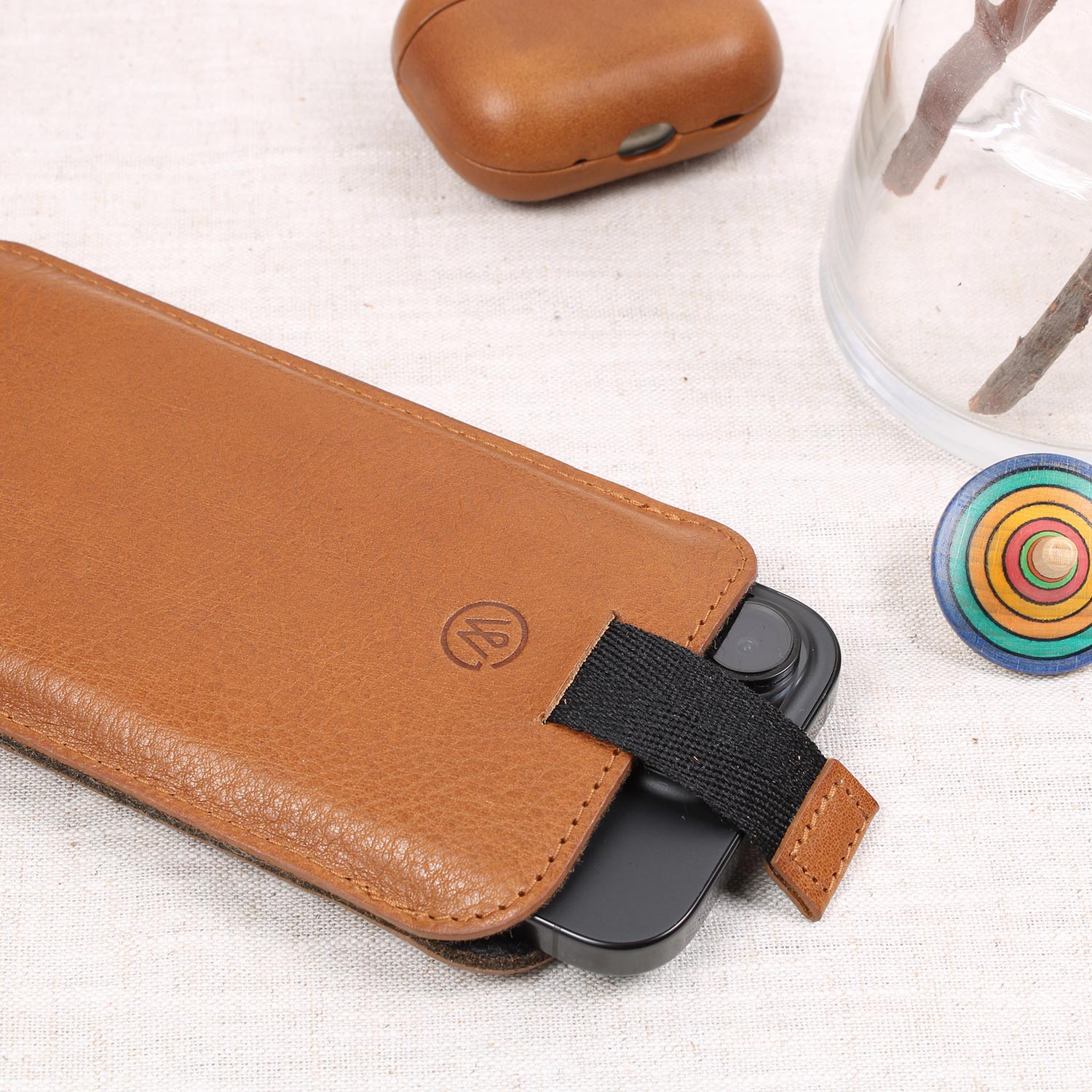 Edle iPhone Leder Hülle in Cognac Braun mit Ziehhilfe – hochwertiges pflanzlich gegerbtes iPhone Sleeve von Good Wilhelm in stilvoller Umgebung.