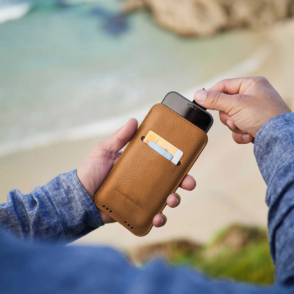 iPhone Leder Sleeve in Cognac Braun von Good Wilhelm in der Hand – Elegante pflanzlich gegerbte iPhone Hülle mit praktischer Ziehhilfe für einfaches Herausziehen des Smartphones.