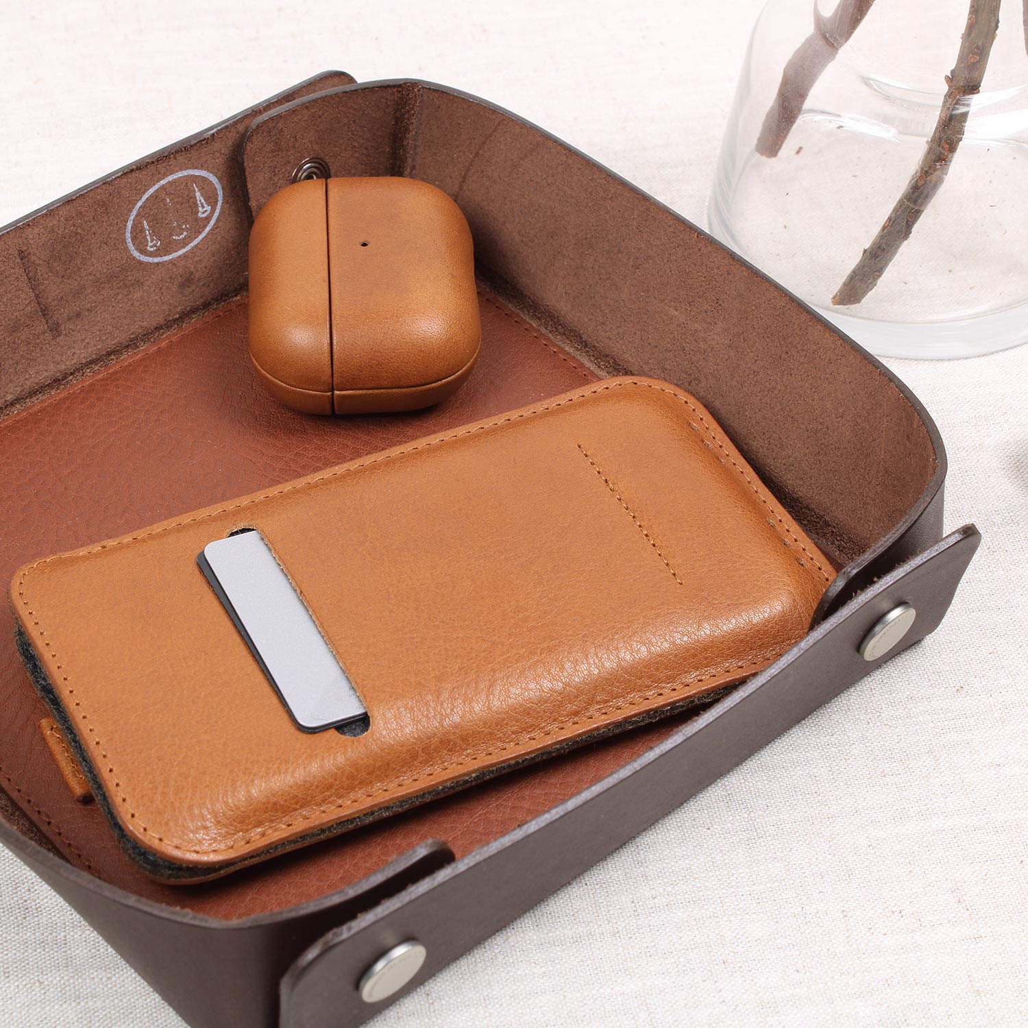 Exklusives iPhone Leder Sleeve in Cognac Braun von Good Wilhelm – Hochwertige iPhone Hülle aus pflanzlich gegerbtem Leder, in einer Ablageschale mit Geldscheinen und Kreditkarten im Vorderfach.