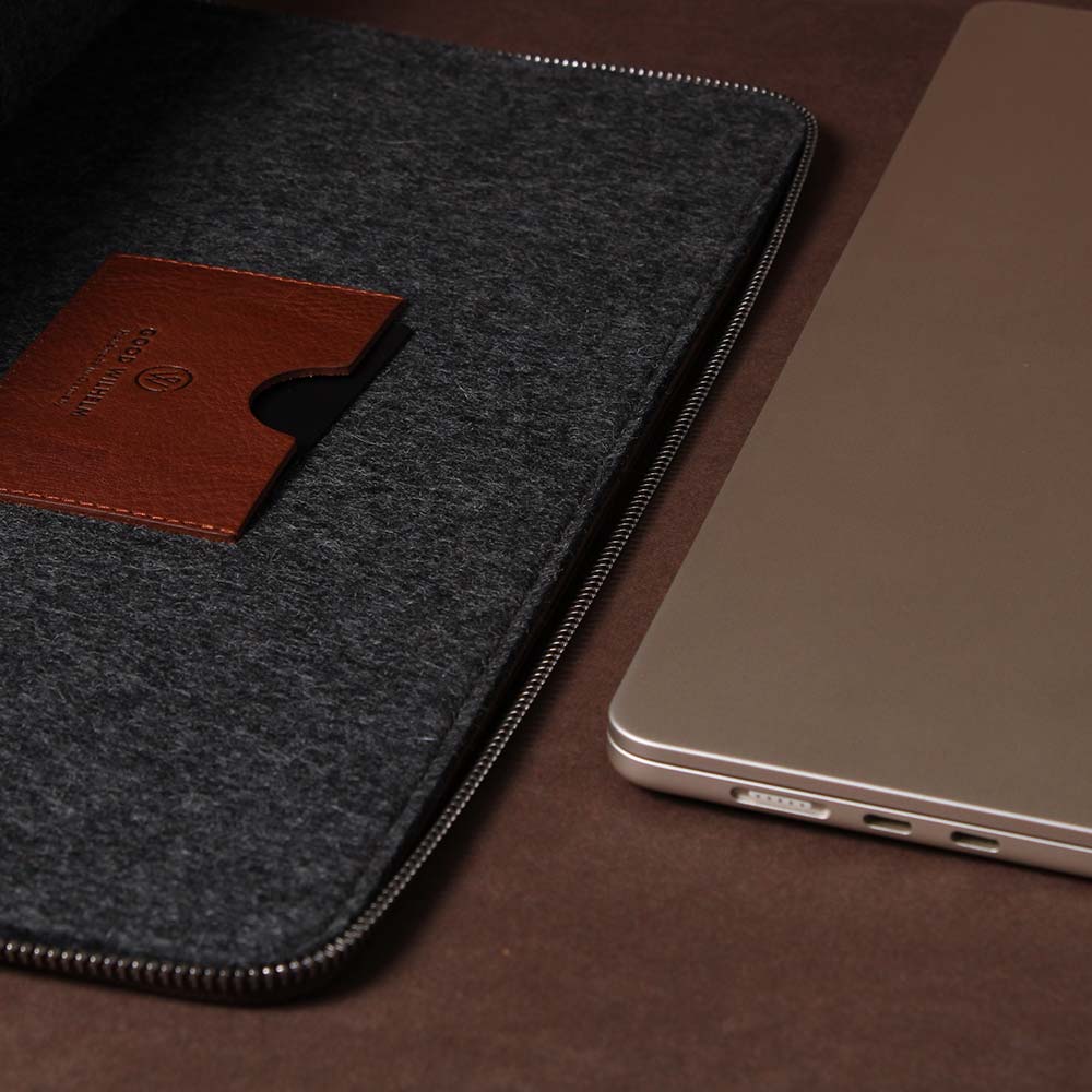 Eine Macbook Hülle aus Filz und Leder liegt neben einem Macbook 