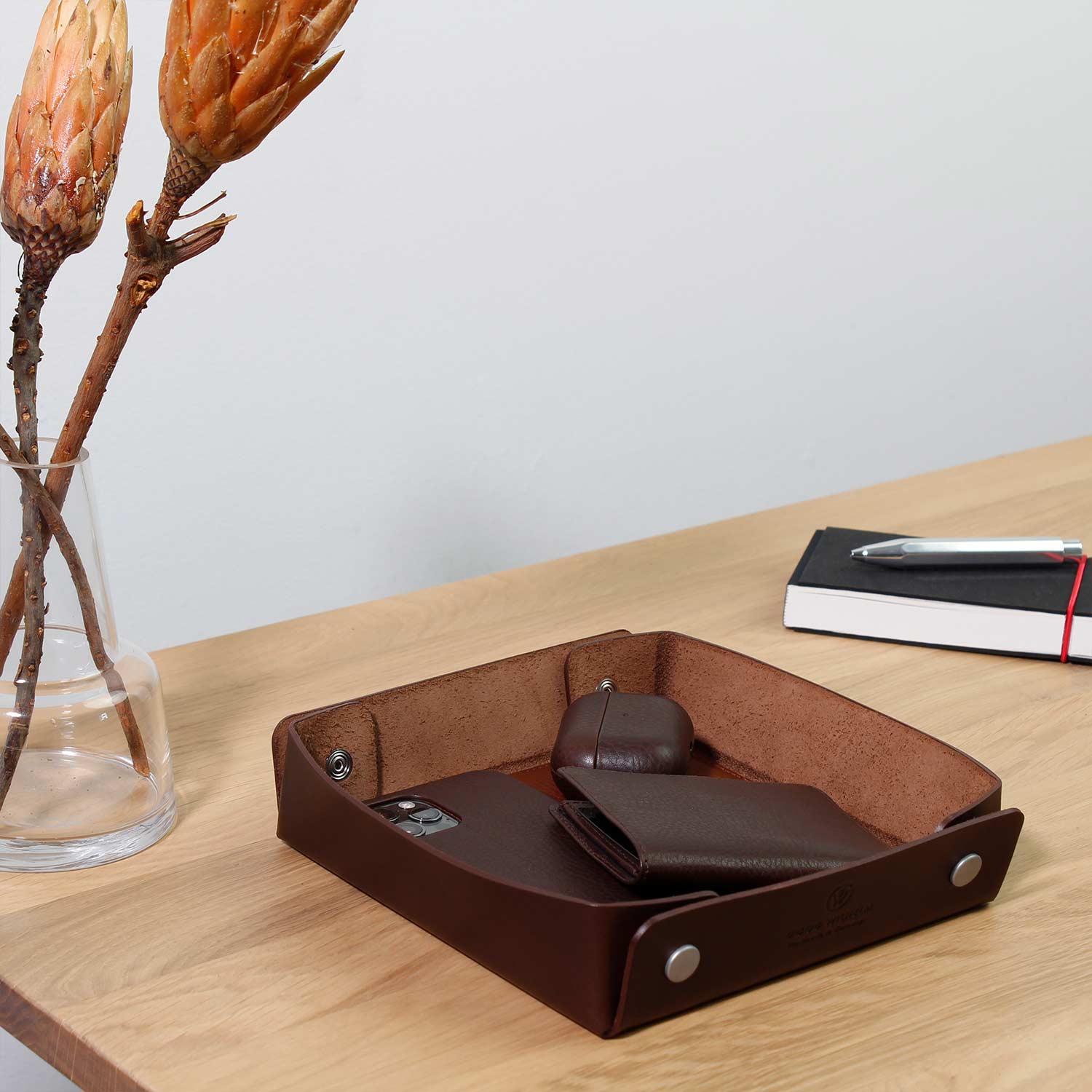 Taschenleerer Leder von Goodwilhelm in der Farbe chocolate mit AirPods, Portemonnaie und Handy drin